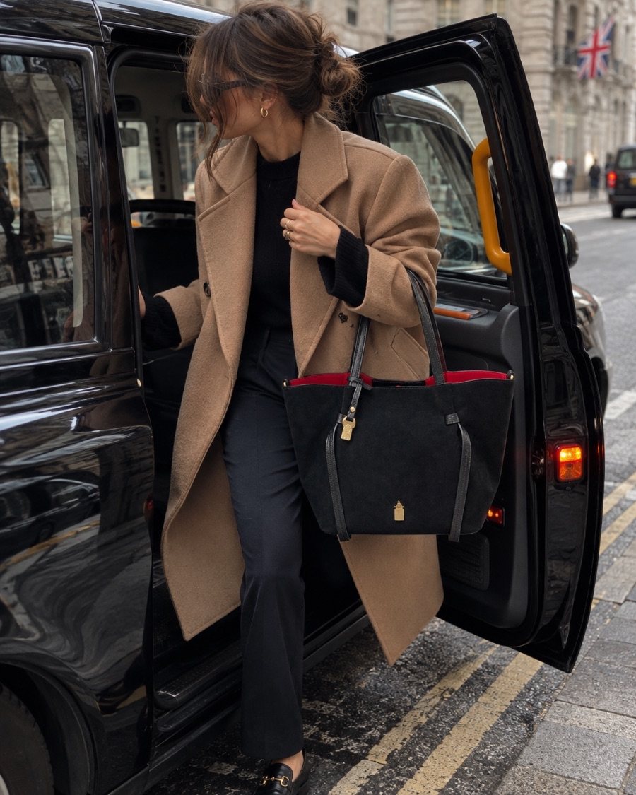Simona in Midnight Black with a camel coat, stepping out of a taxi