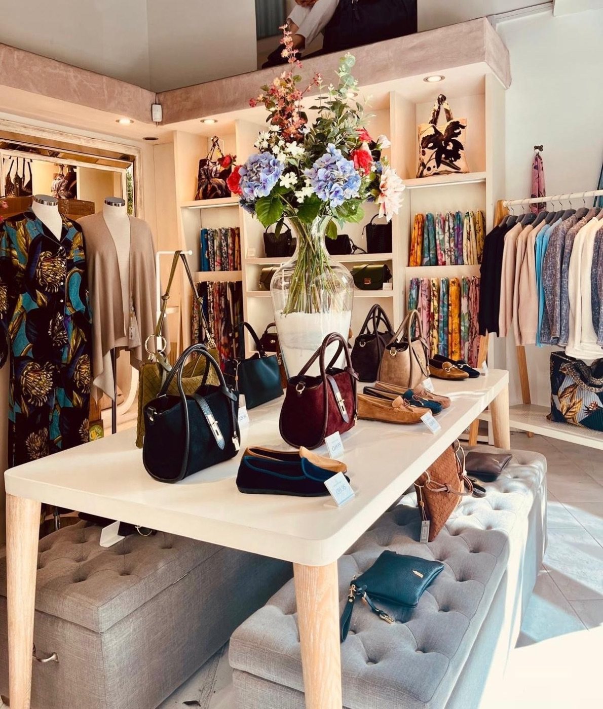 Inside the Franchetti Bond store: suede handbags and loafers on a white table beneath a vase of hydrangeas