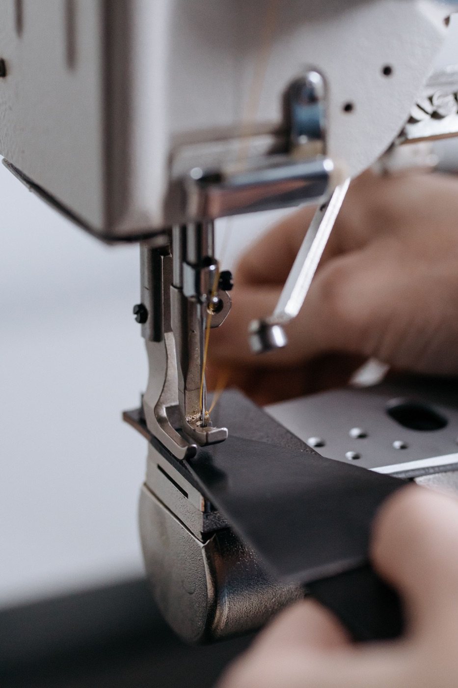 Leather being fed through an industrial sewing machine under a close-set stitch