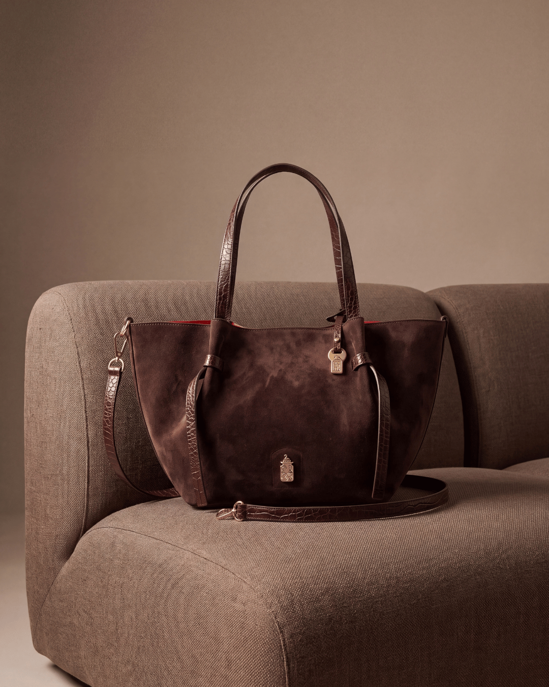 Simona in Rich Chocolate on a linen sofa, with its detachable shoulder strap